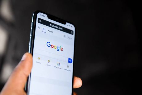 Person holding black Android smartphone with Google search page on screen.
