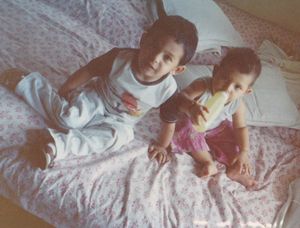 My sister (right) and I (left) as children sitting on a bed.